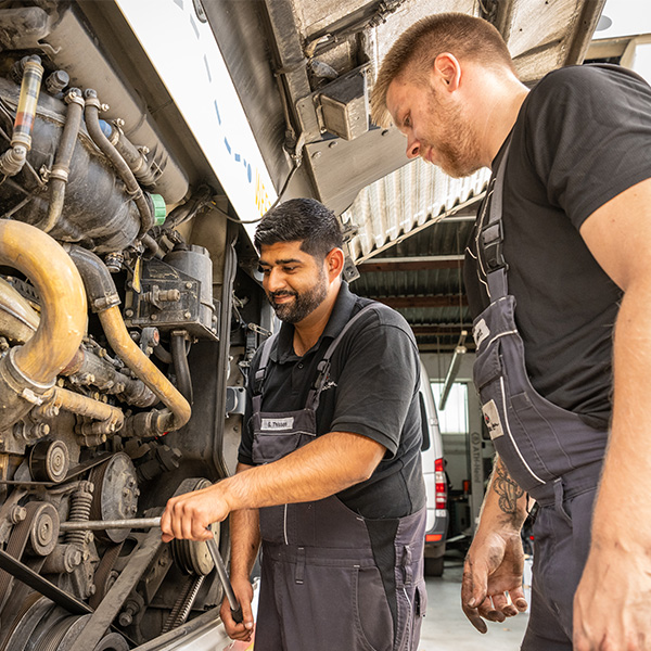 Zwei Mitarbeiter, die bei Verhuven als Nutzungsmechatroniker arbeiten und einen Bus reparieren
